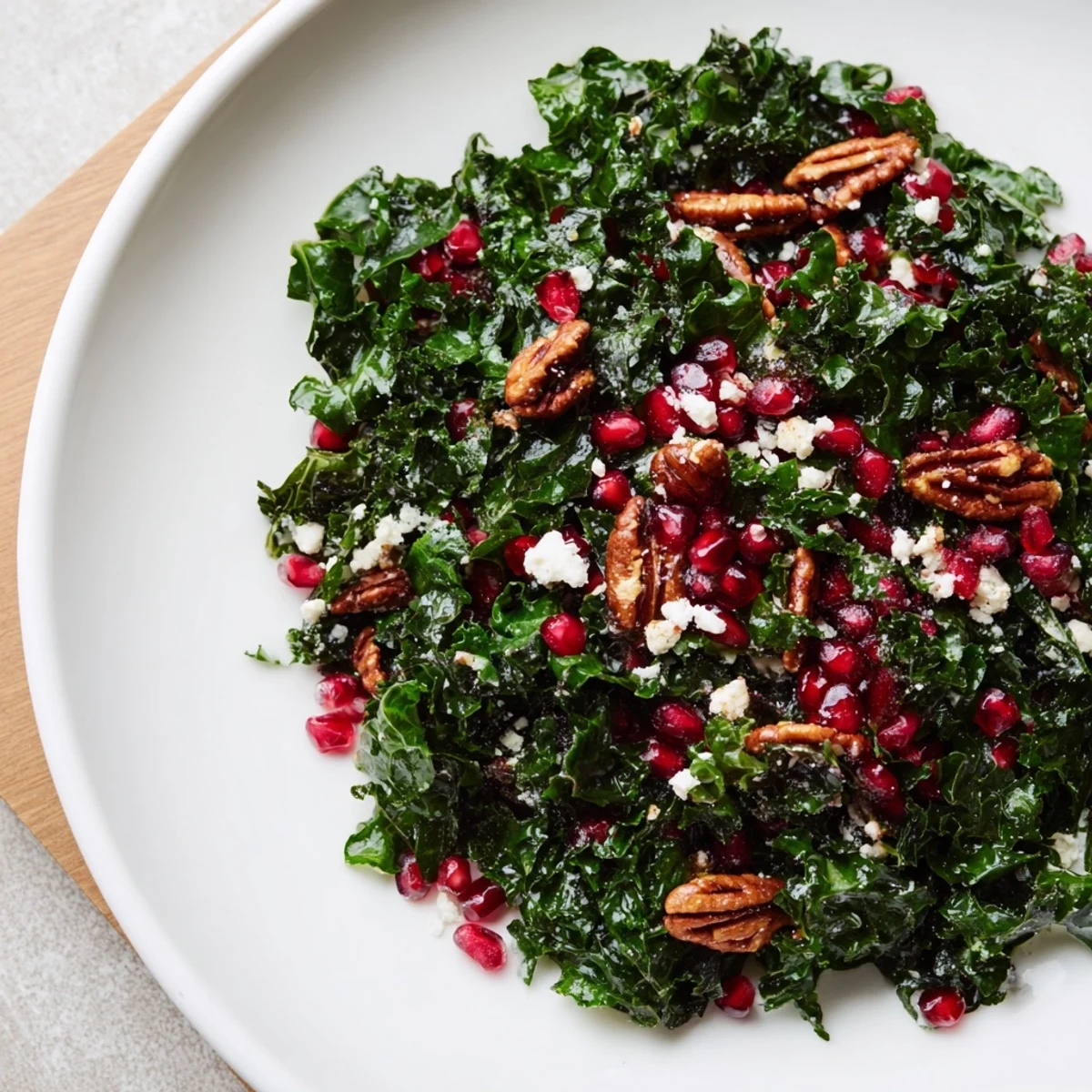 Close-up of a vibrant Winter Kale Salad with Pomegranate and Pecans, featuring emerald greens, ruby seeds, and golden toasted nuts tossed in citrus dressing.
