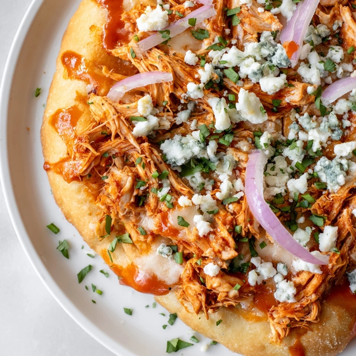 Sliced MVP Buffalo Chicken Pizza reveals spicy chicken, mozzarella, and ranch dressing drizzle on a casual table.