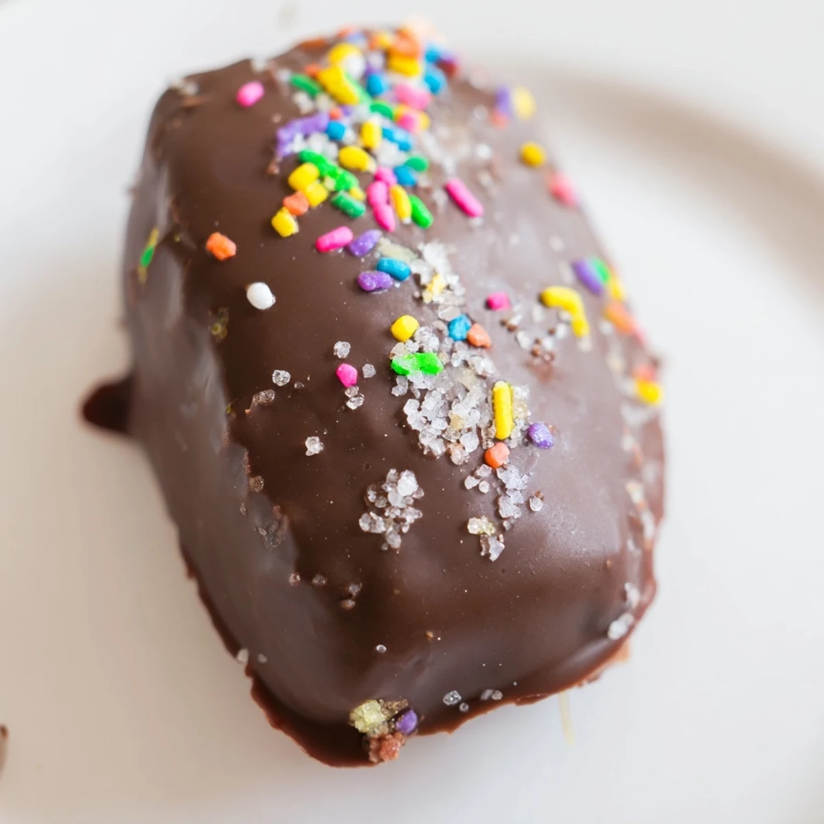 Two chocolate covered Peeps stacked on a marble countertop, showing the marshmallow center and drizzled chocolate for a whimsical treat.