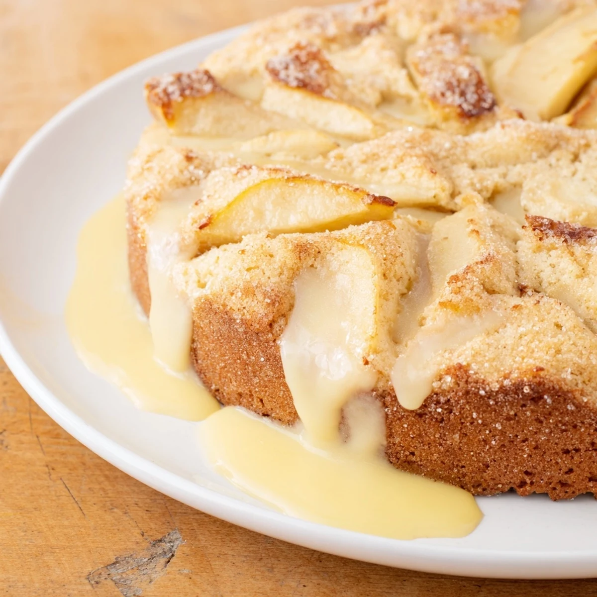 A slice of Irish Apple Cake rests on a plate, drizzled with creamy homemade vanilla custard and ready to enjoy.