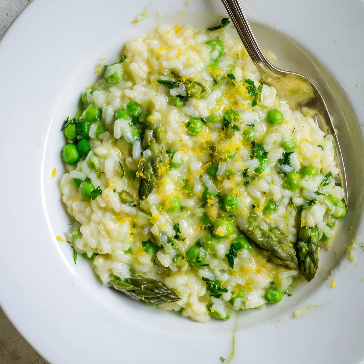 A warm bowl of Spring Pea and Asparagus Risotto garnished with fresh parsley, showcasing tender green vegetables in a creamy, comforting texture.  