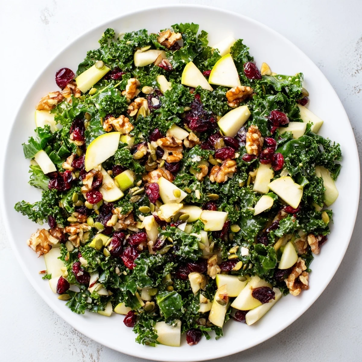 A close-up of Winter Kale Salad with Apple and Cheddar showcasing crisp apple slices and toasted pecans on fresh greens.