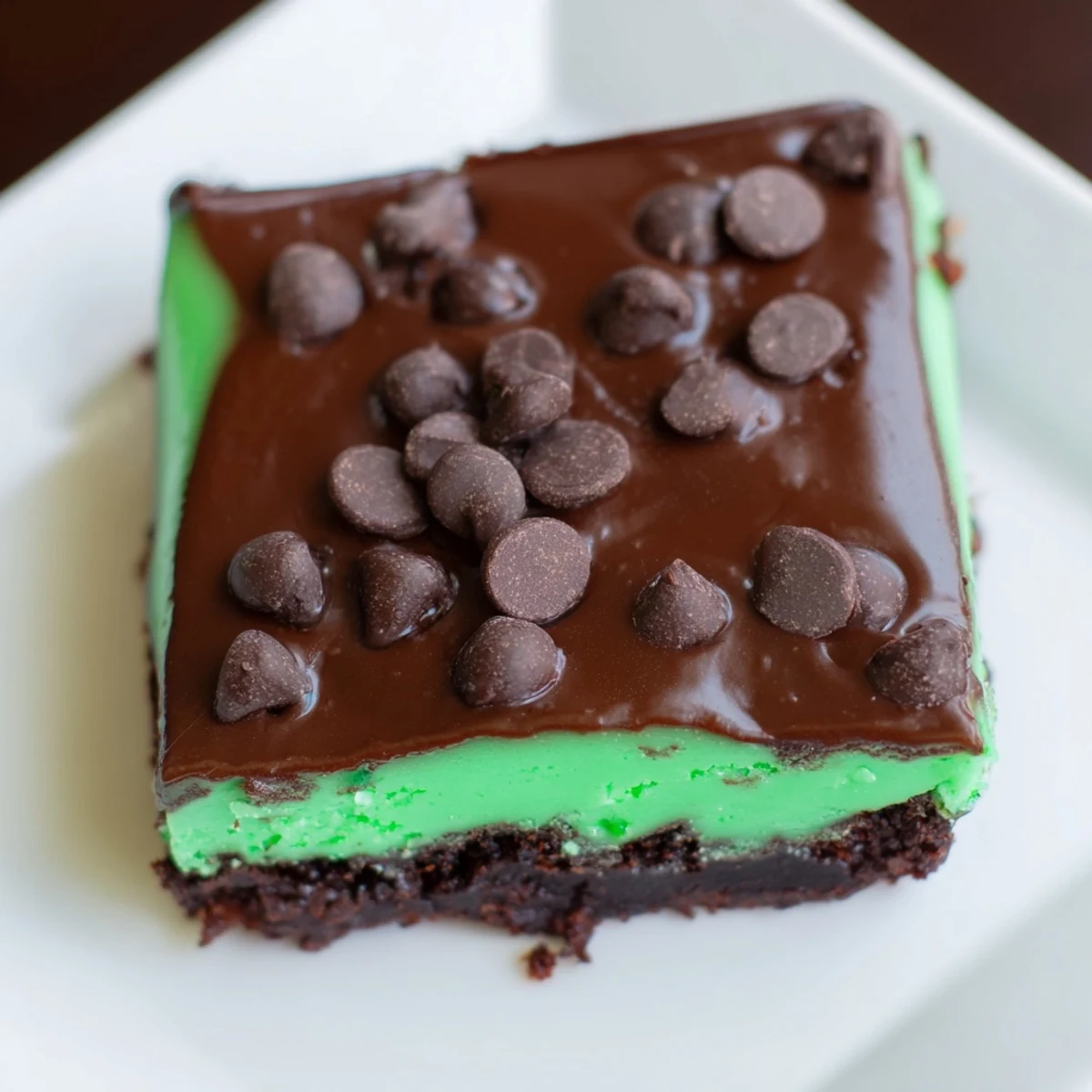 Green mint brownies with chocolate chips are cut into squares, perfect for a festive American dessert.