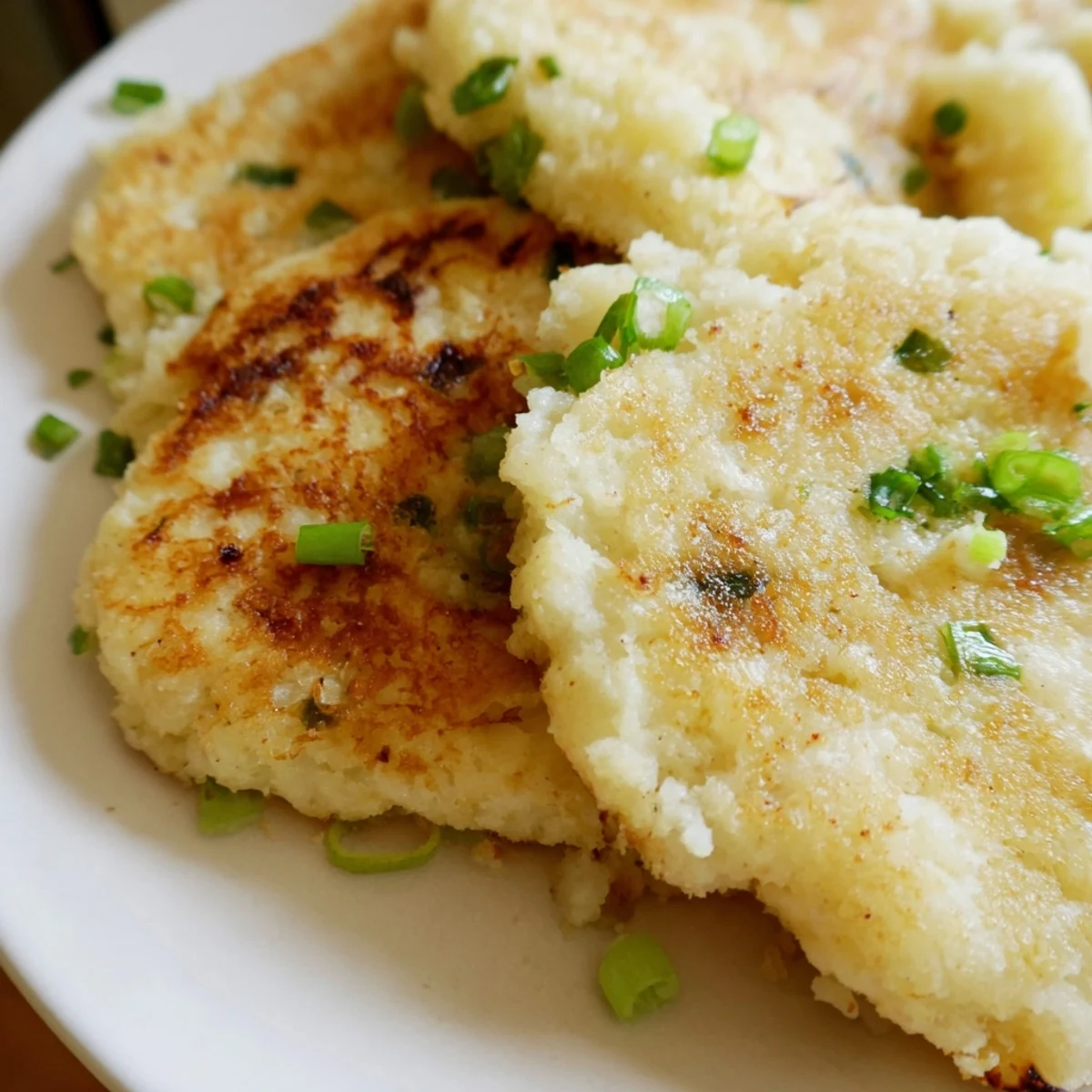 A close-up of Irish Potato Cakes with Scallions, garnished with fresh greens beside a cup of tea.