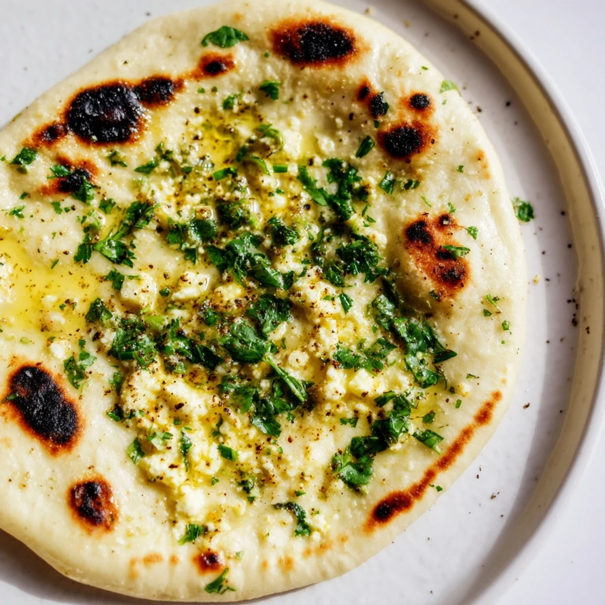 Warm Cottage Cheese Garlic Naan served beside a bowl of spicy curry, ready to scoop up the sauce.