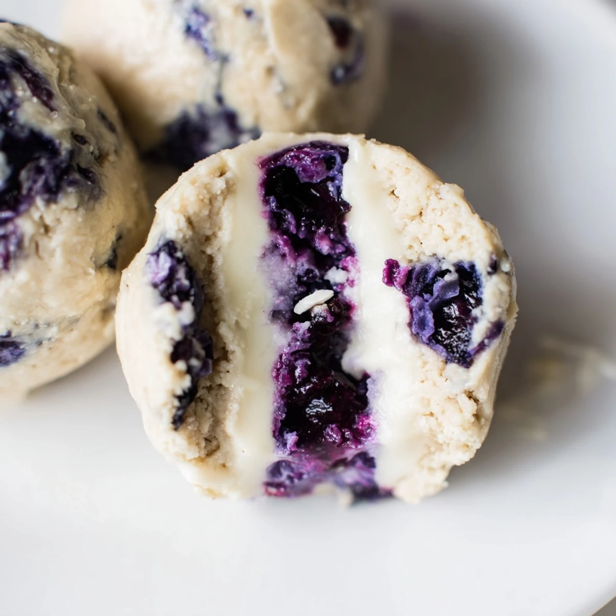 Fresh Blueberry Cheesecake Protein Bites on a white plate with graham cracker crumbs.