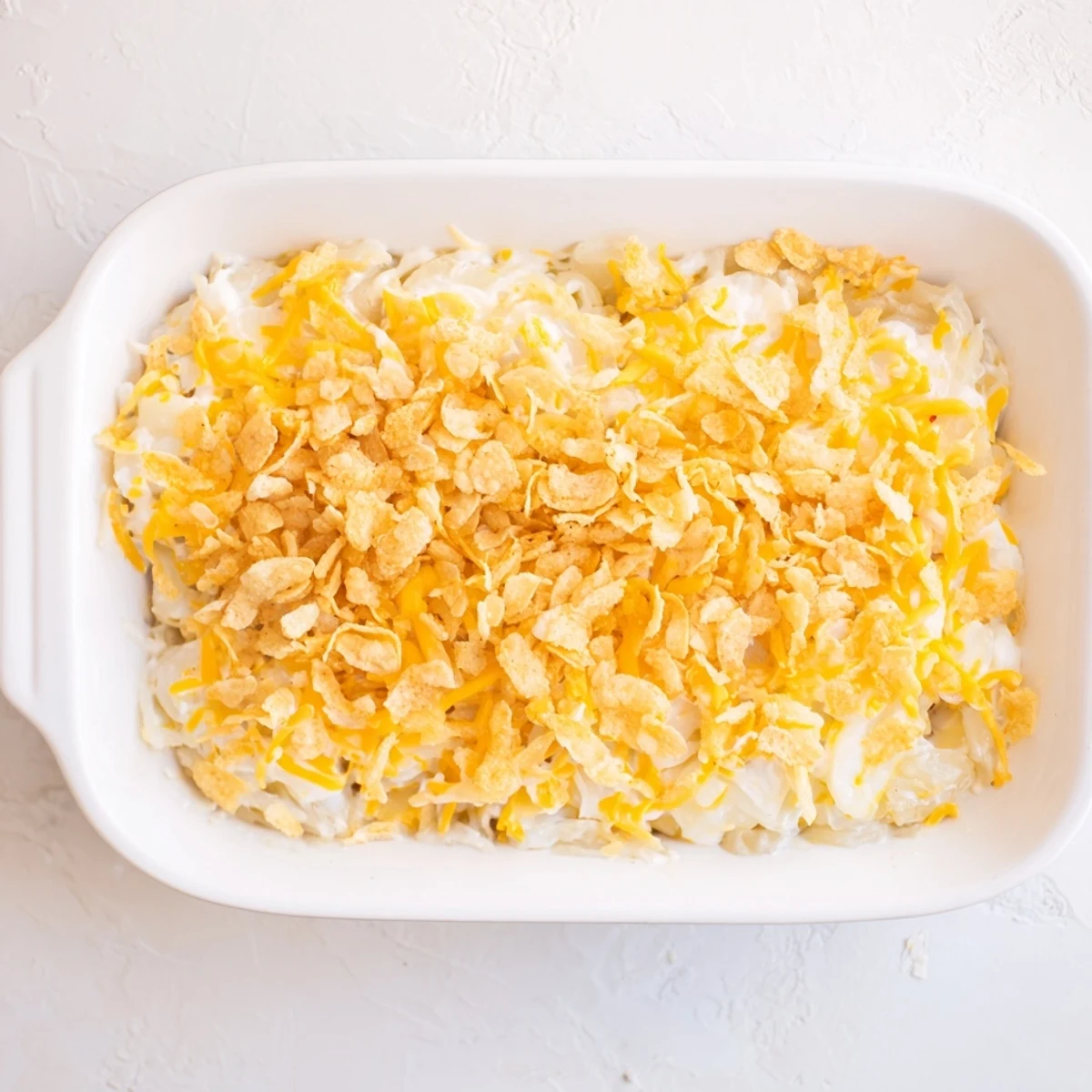 Golden-brown Funeral Potatoes with Hashbrowns emerge from the oven with a crispy cornflake topping, ready to serve at a holiday potluck.
