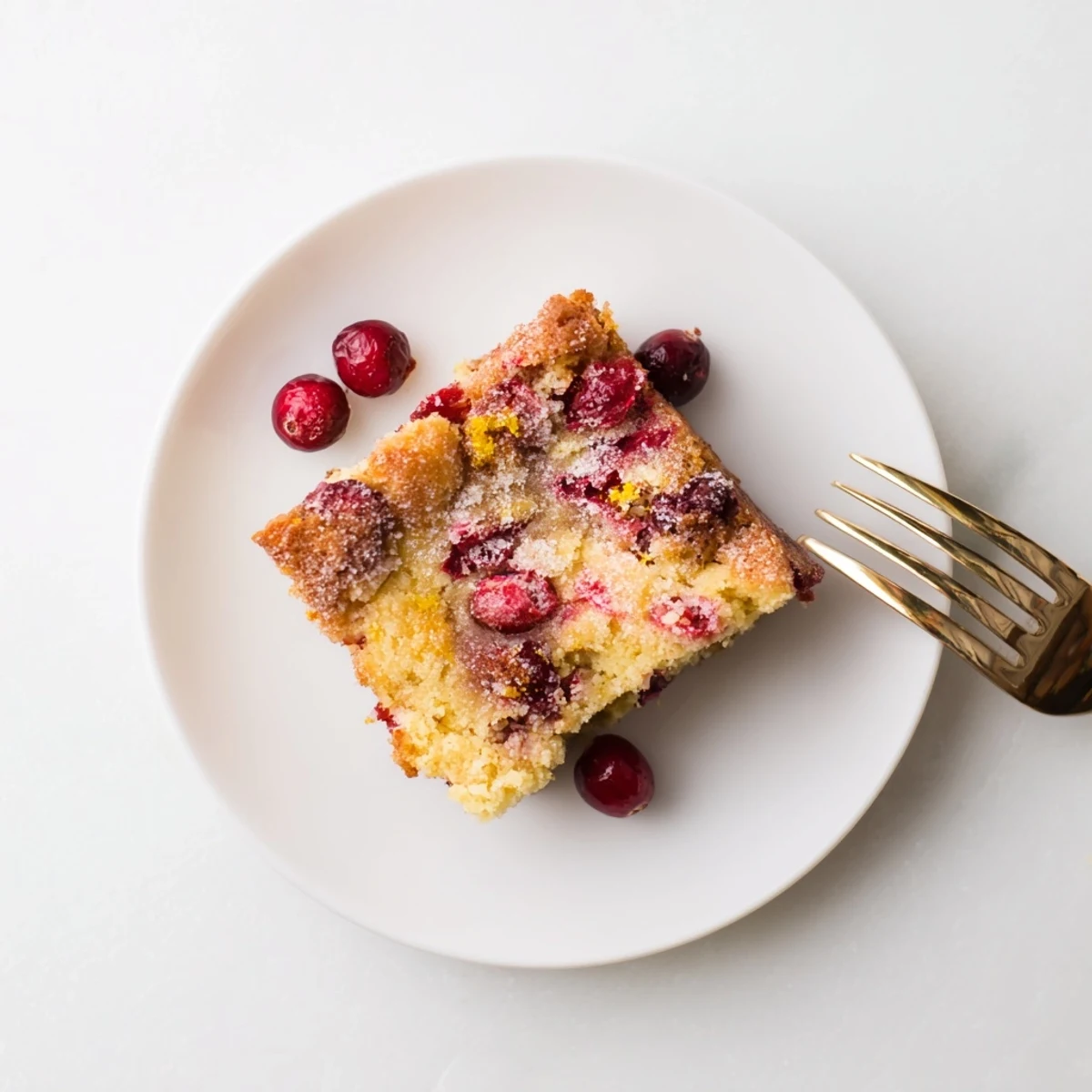 Holiday Cranberry Cake cooling on a wire rack, showing a tender, buttery interior packed with juicy, vibrant cranberries.