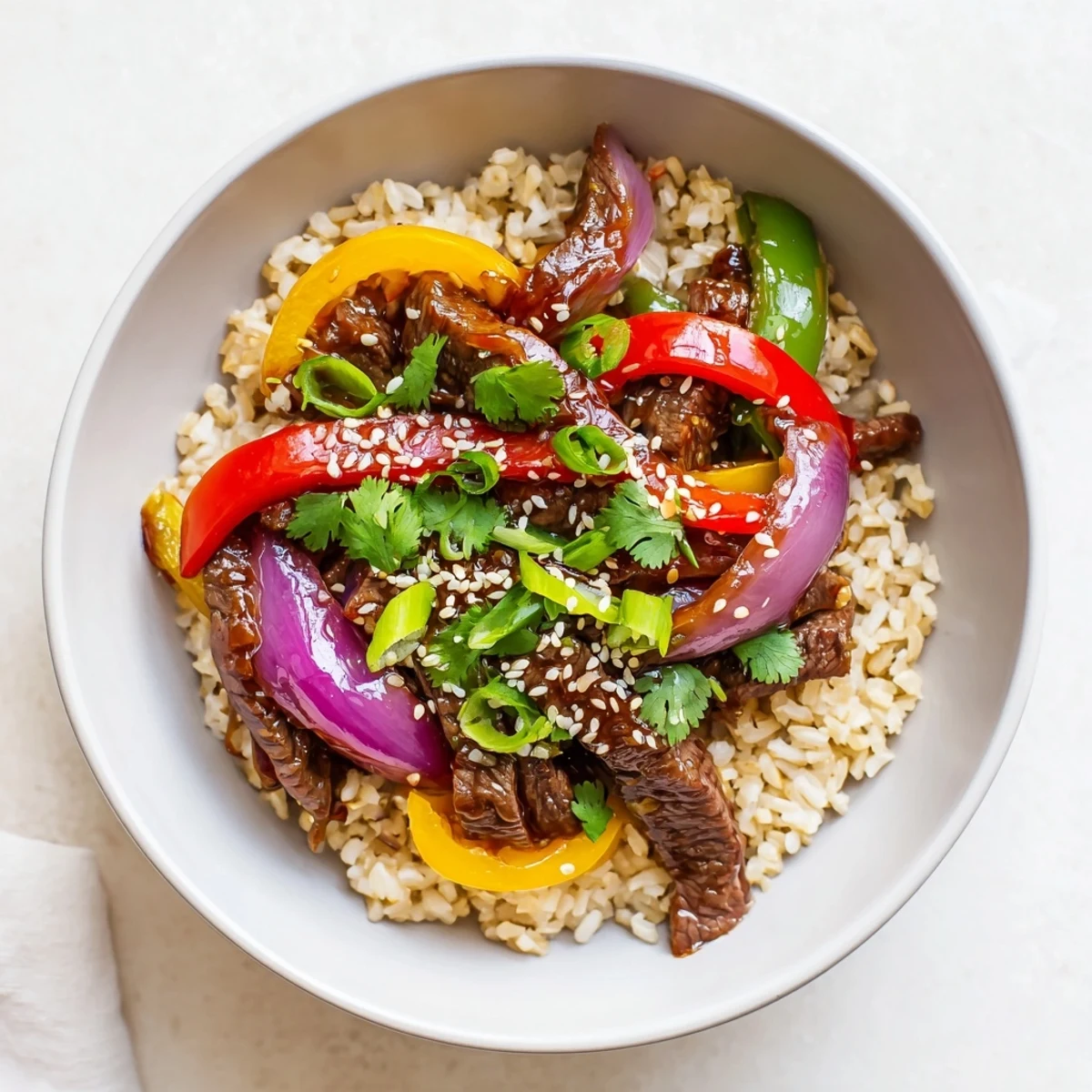 Healthy beef and pepper rice bowl featuring tender strips of steak sautéed with crisp colorful bell peppers and aromatic garlic-ginger sauce over fluffy brown rice