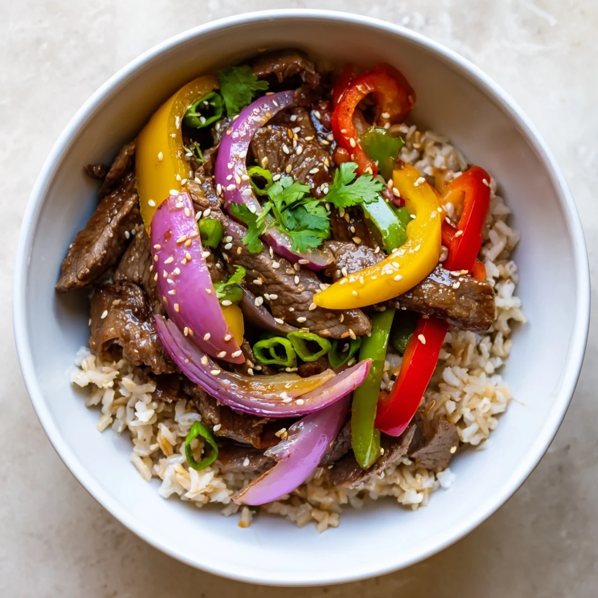 Savory healthy beef and pepper rice bowl showcasing marinated sirloin, rainbow bell peppers, and red onions in a sweet and tangy Asian-inspired glaze