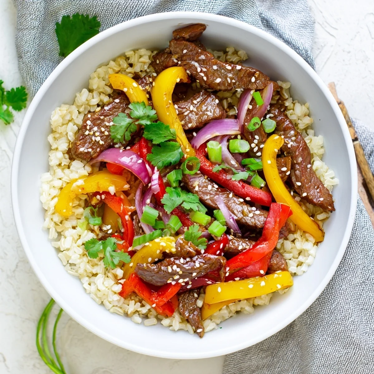 Vibrant protein-packed healthy beef and pepper rice bowl garnished with fresh spring onions, toasted sesame seeds, and cilantro for a satisfying balanced meal