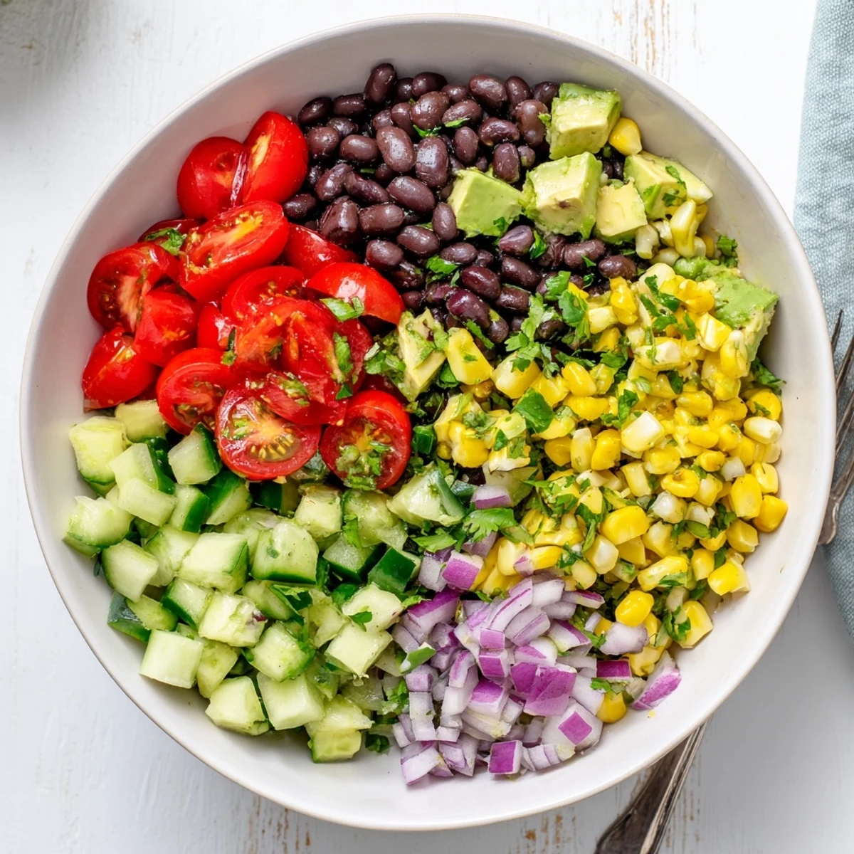 Fresh chopped black bean salad bowl with ripe avocado chunks, cherry tomatoes, red onion, and crisp corn for a healthy meal