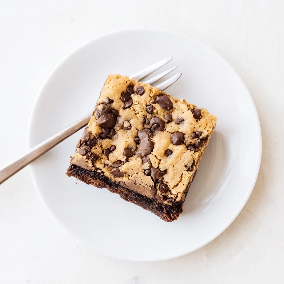 Freshly baked chocolate chip cookie brownies sliced into squares on a wooden serving board
