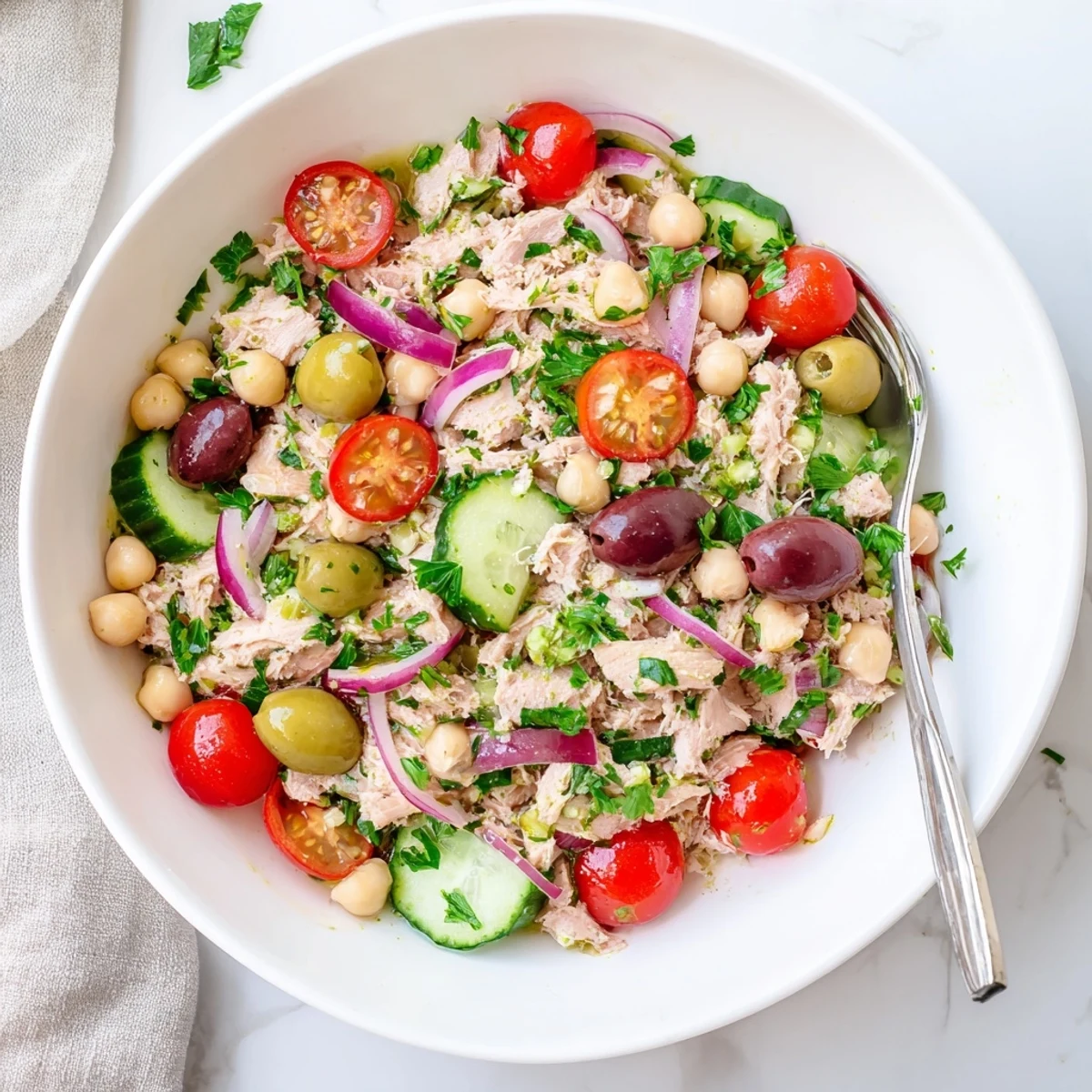 Mediterranean-inspired hearty tuna and garbanzo bean salad featuring cherry tomatoes, cucumber, olives, and fluffy garbanzo beans