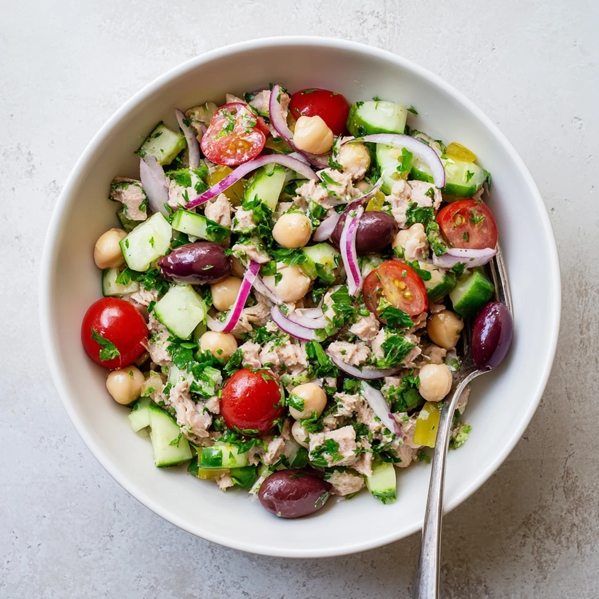 Protein-packed hearty tuna and garbanzo bean salad plated with crisp red onion, parsley, and tangy herb coating