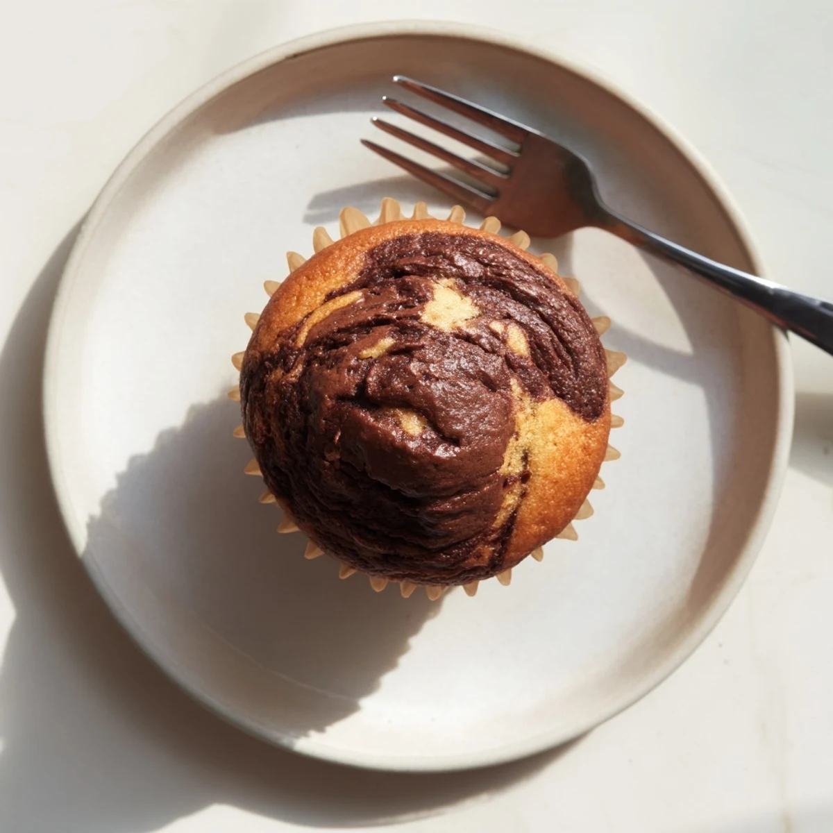 Freshly baked Nutella banana swirl muffins with golden tops and rich chocolate ribbons swirled through moist banana bread