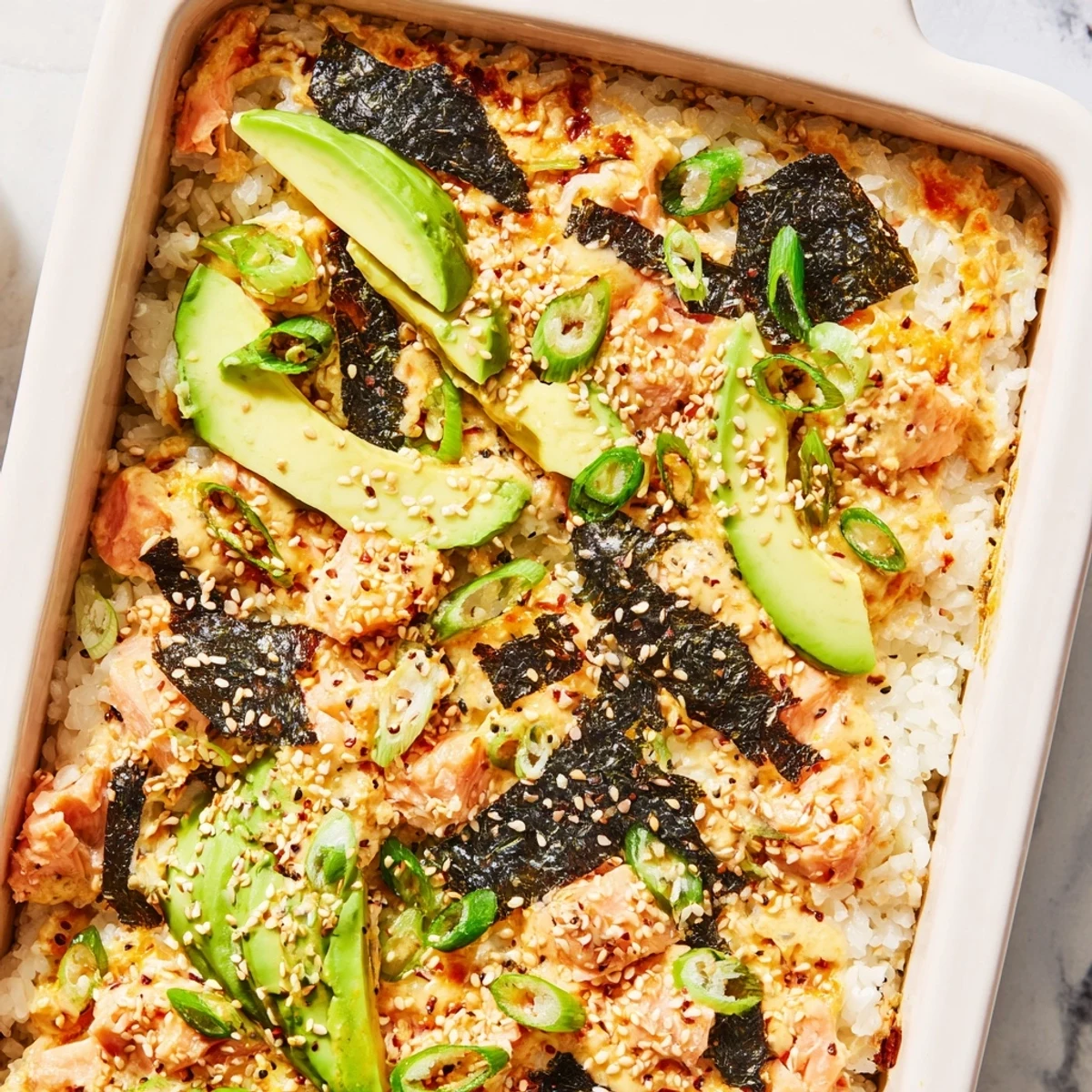 Golden salmon sushi bake with fluffy rice, spicy mayo, and fresh avocado garnish