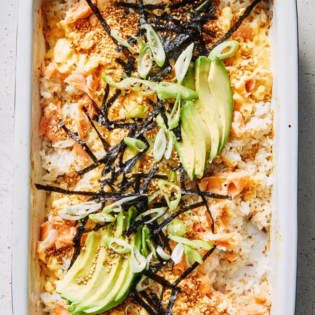 Warm deconstructed salmon sushi bake casserole topped with nori strips and sesame seeds