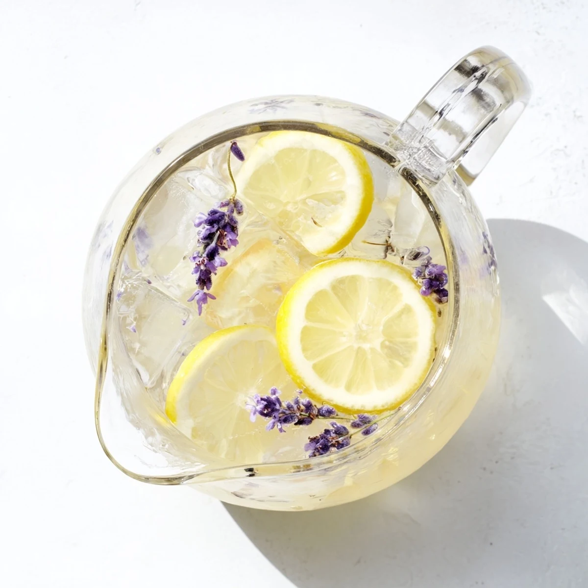 Golden purple lavender lemonade in mason jars with ice cubes and lemon wheel garnish