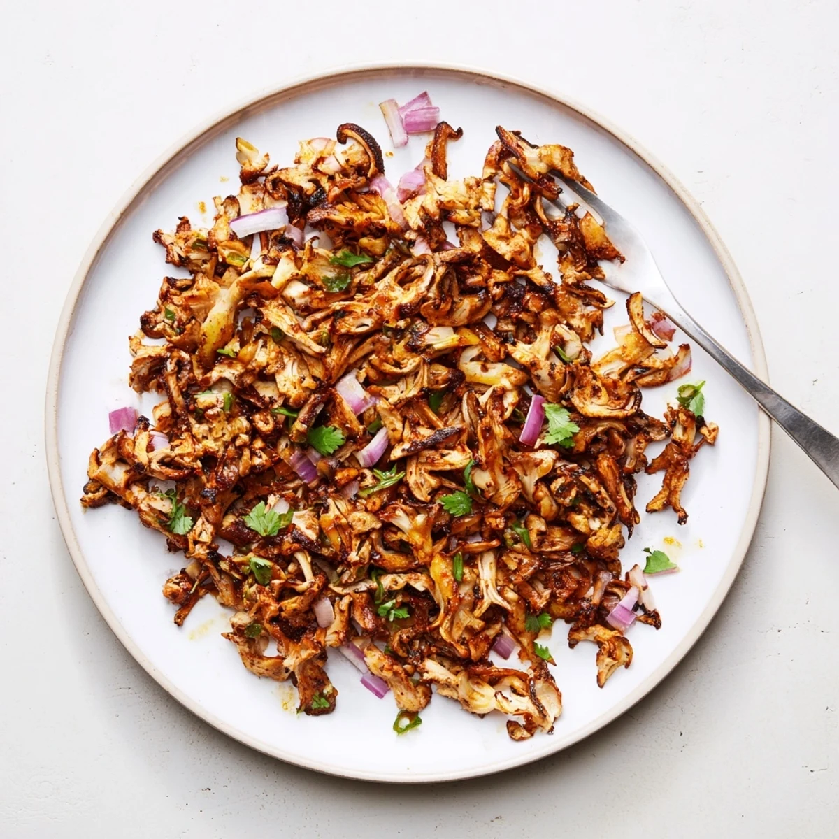 Golden brown vegan carnitas with shredded mushrooms piled in warm corn tortillas