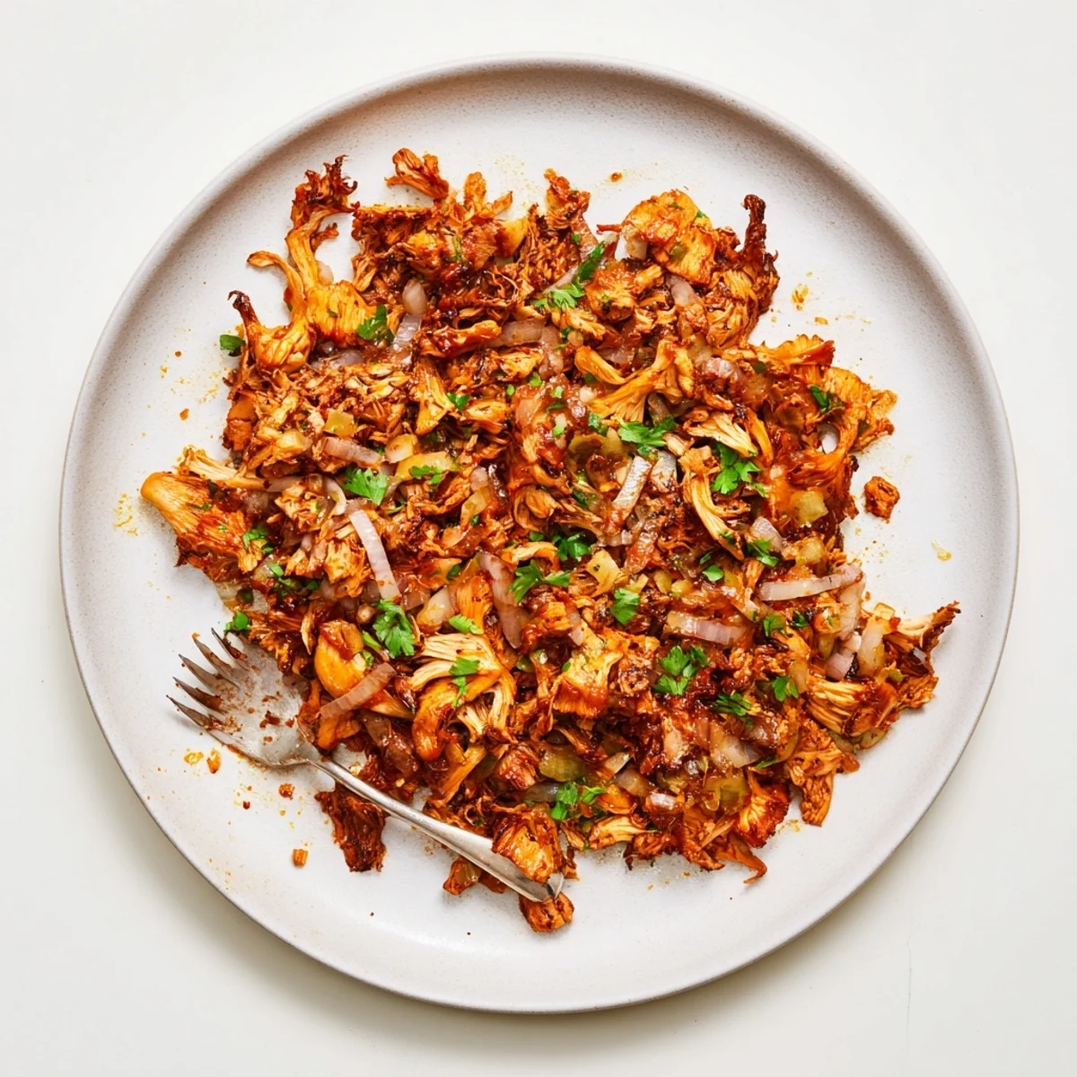 Crispy baked vegan carnitas featuring seasoned mushrooms served with lime and avocado