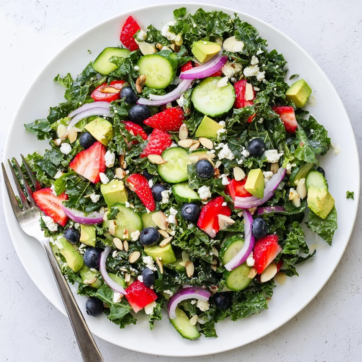 Vibrant summer kale salad bowl with sliced avocado, blueberries, and crunchy almonds