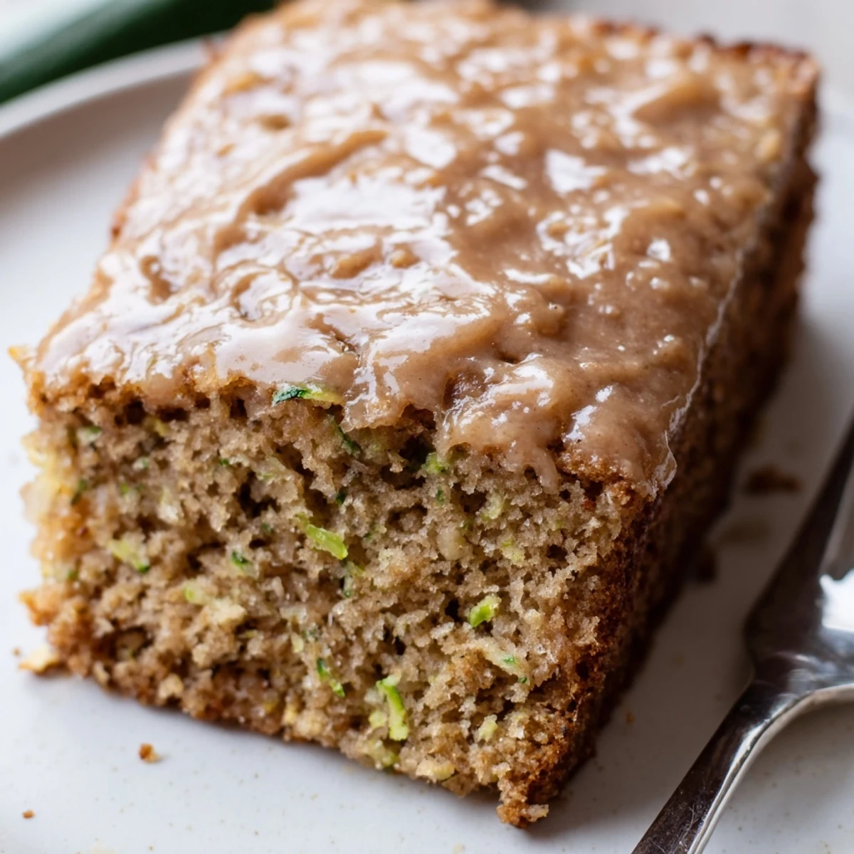 Slice of Zucchini Cake With Brown Sugar Icing on a rustic wooden board  