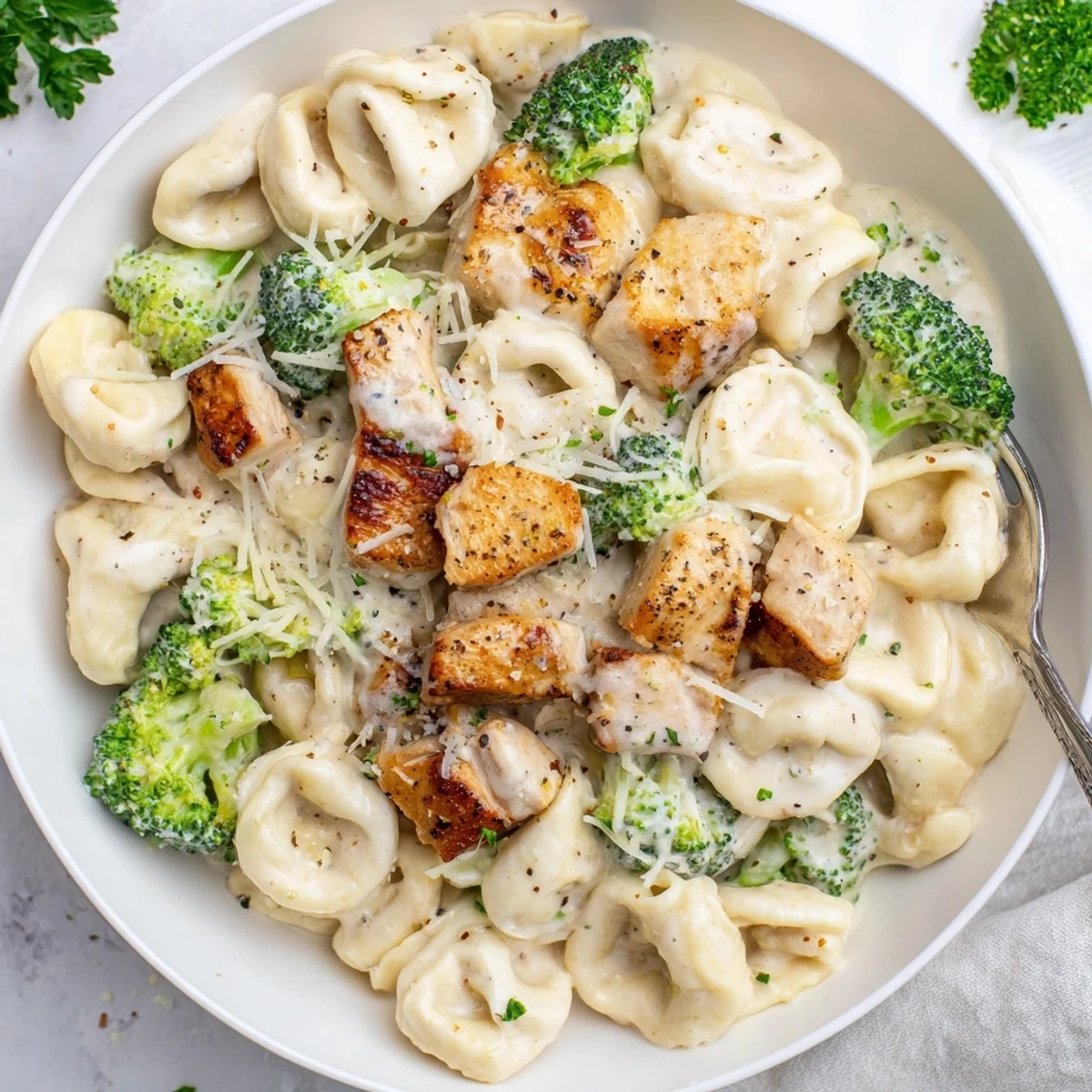 Fork-twirled Creamy Garlic Parmesan Tortellini Chicken Broccoli Recipe with juicy chicken bites