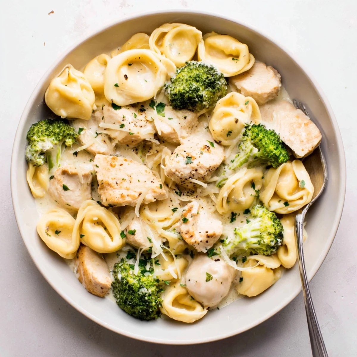 Plate of Creamy Garlic Parmesan Tortellini Chicken Broccoli Recipe garnished with fresh parsley