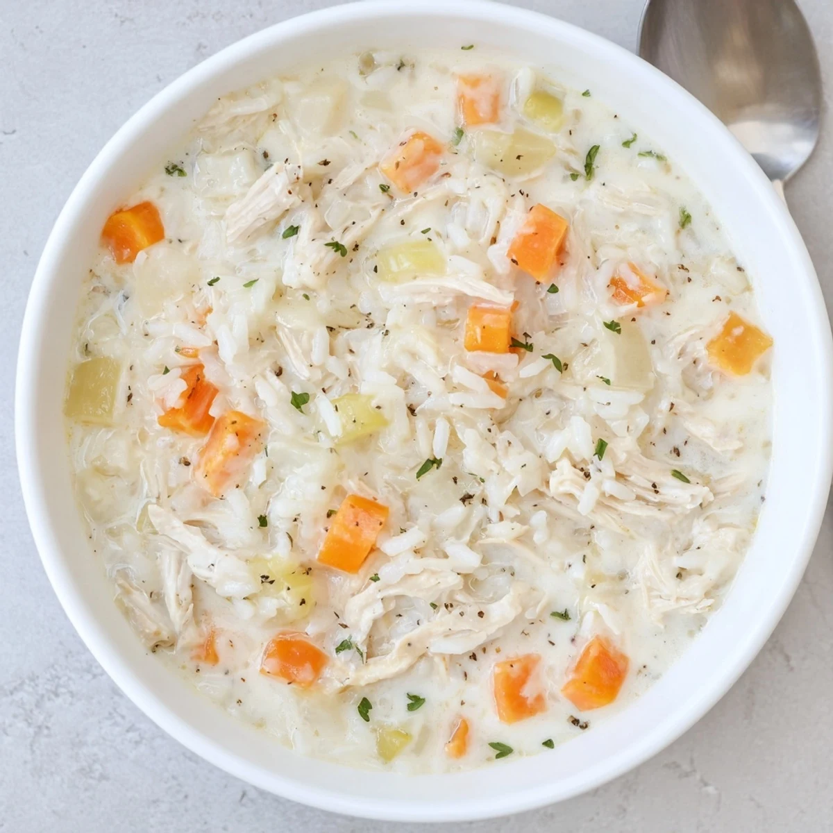 Bowl of Creamy Chicken Rice Soup with diced carrots, savory aroma