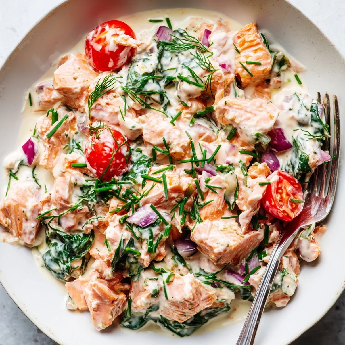 Creamy leftover salmon recipe served hot in a skillet with fresh dill sprinkled on top
