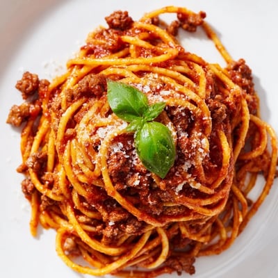 A close-up view of The Bear Spaghetti featuring hearty ground beef sauce and grated Parmesan cheese ready to serve.