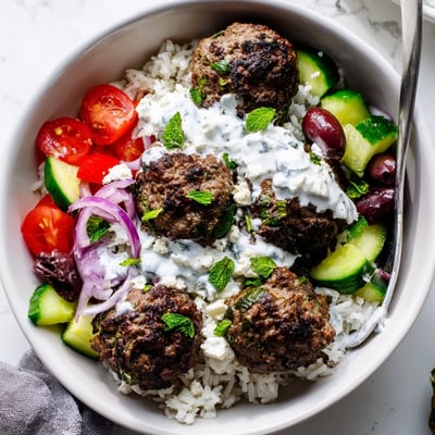 Golden pan-fried Greek meatball bowl served over rice with cherry tomatoes and olives